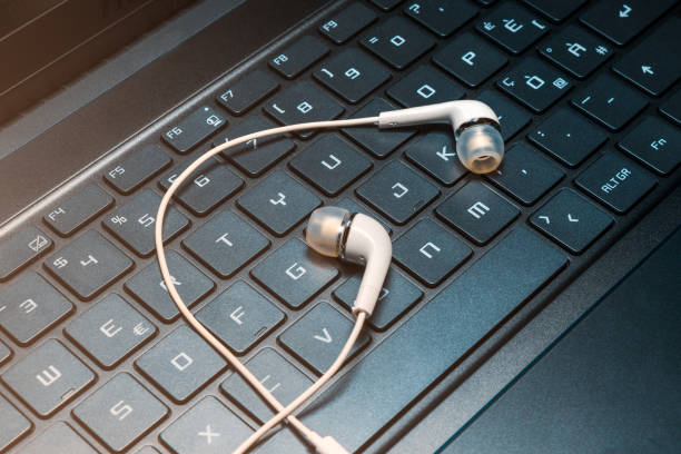 A pair of white earphones on a laptop keyboard stock photo