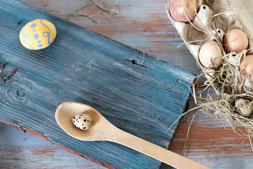 Eggs, quail, easter decor on a blue wooden table, top view