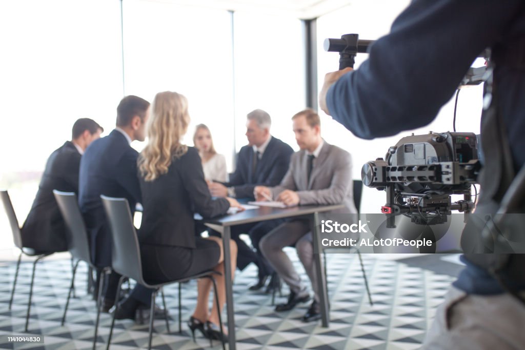 Videographer filming business meeting Videographer filming group of people at business meeting Movie Stock Photo