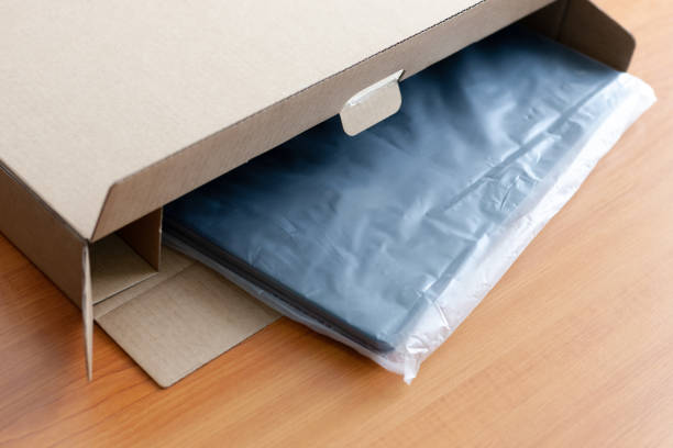 unpacking new blue laptop at wooden desk. cellophane packaging. post and delivery concept. stock photo