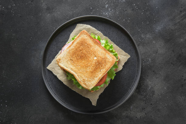 istock Sandwich with bacon, tomato, onion, salad on black background. Isolated. View from above. 1141054149