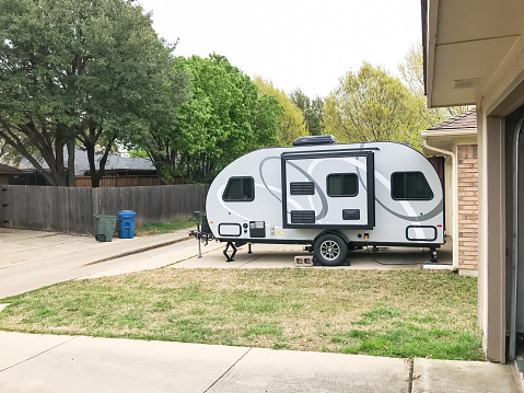 Side view of RV trailer parked at house garage backyard