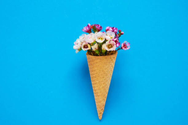 istock Ice cream cone with small flowers on blue background. Copy space, top view. 1141055589