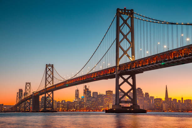 horizonte de san francisco con oakland bay bridge al atardecer, california, usa - golden gate bridge night bridge san francisco bay fotografías e imágenes de stock