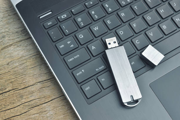 Close up of metal USB flash drive connected to laptop on wood desk stock photo