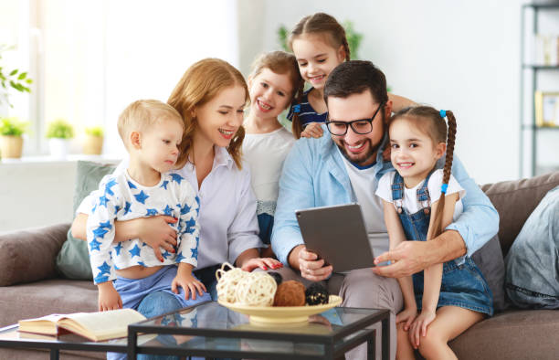 grande mère de famille, père et enfants avec l’ordinateur de tablette à la maison - people child twin smiling photos et images de collection