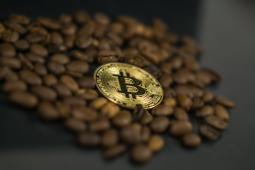 Photo of Bitcoin cryptocurrency coin as payment currency surrounded with coffee beans