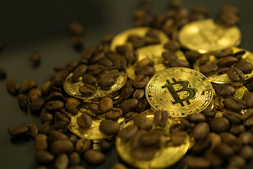 Photo of Bitcoin cryptocurrency coin as payment currency surrounded with coffee beans