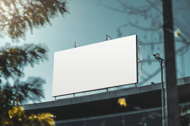 Mockup of the banner on the rooftop An empty huge poster mockup on the roof of a mall; white template placeholder of an advertising billboard on the rooftop of a modern building framed by trees; blank mock-up of an outdoor info banner commercial sign stock pictures, royalty-free photos & images