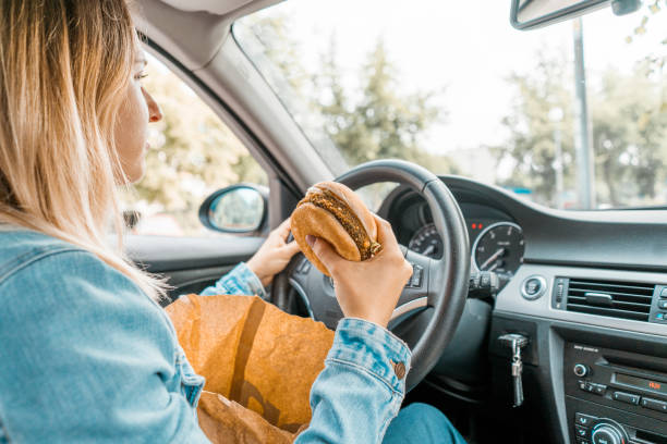 istock Woman holding burger while driving 1141083587