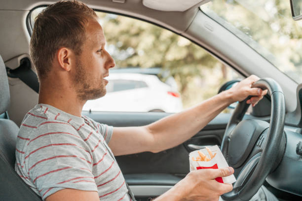 istock Young man holding fries while driving 1141083611