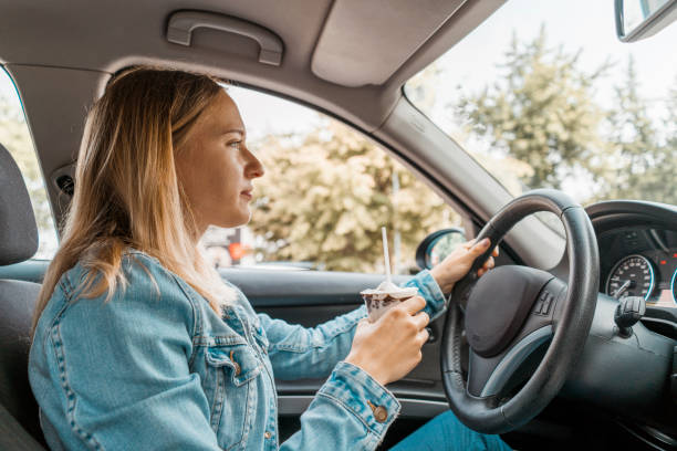 istock Young woman eating ice cream while driving 1141083732