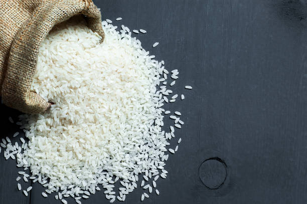 tureckie surowe białe ziarna ryżu w worku burlap na czarnym drewnianym tle - rice cereal plant white rice white zdjęcia i obrazy z banku zdjęć
