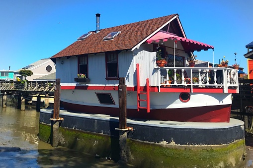 Sausalito, California, USA/April 12, 2019: A brightly colored, cheerful fairy tale houseboat lit by the sun in Sausalito, California
