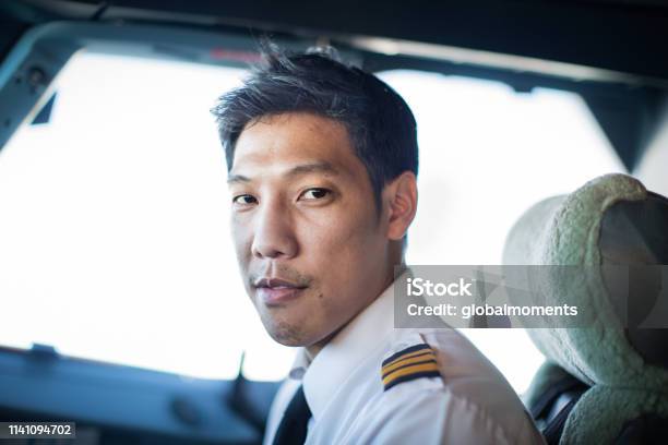 Portrait Of A Male Pilot Sitting In The Cockpit Stock Photo - Download Image Now - Pilot, Piloting, Asia