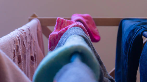 istock Focus on a pink sock drying on a laundry rack with other woman's clothes, and mismatched socks blurred in the foreground. Depicting laundry day, chores, cleaning, unmatched socks, finding socks, etc. 1141098567