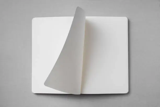 Photo of white notebook with turn page on grey background