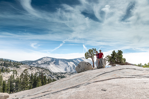 Couple sitting on a boulder and posing for a photograph at Olmsted Point, Yosemite park