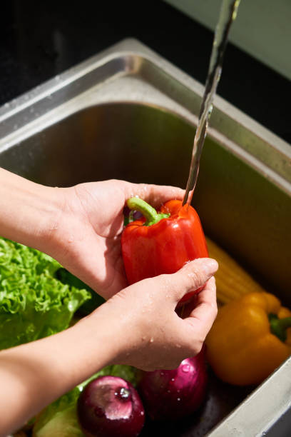istock Person rinsing red bell pepper 1141113432