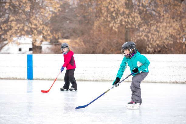 Two Girls Playing Outdoor Ice Hockey on Winter Day stock photo