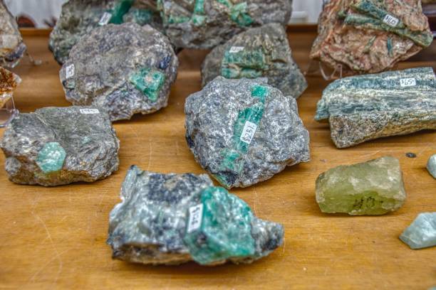 grober smaragd eingebettet in stein in einem rock shop - beryll mineral stock-fotos und bilder