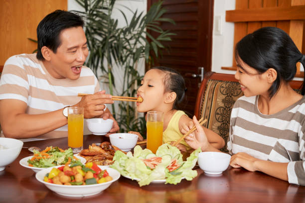 Father feeding daughter at dinner