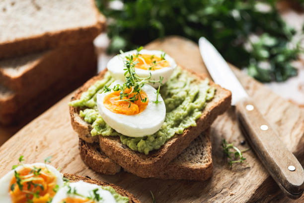 Healhy Breakfast Toast With Avocado, Egg Healhy Breakfast Toast With Avocado, Boiled Egg On Wooden Cutting Board avocado stock pictures, royalty-free photos & images
