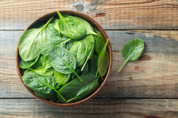 istock Fresh spinach leaves in bowl on wooden table. 1141121343