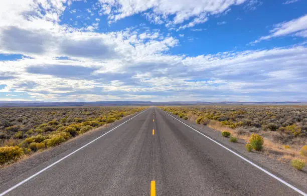 "The loneliest road in America US 50" A view of the endless road, Highway 50 in Nevada. You see the empty road, Nevada desert and a cloudy blue sky. Nevada, USA.