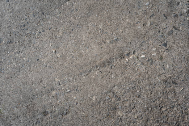 Dark asphalt road surface texture with embedded grit and stones