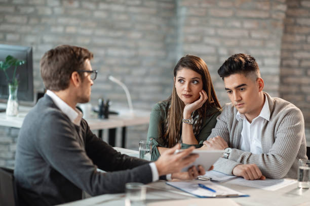 istock Young couple and their bank manager talking while using touchpad on a meeting. 1141144687