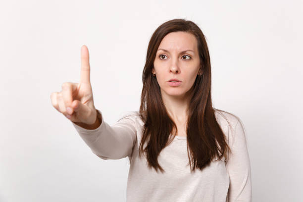 istock Serious young woman touch something like push click on button pointing at floating virtual screen isolated on white background in studio. People sincere emotions lifestyle concept. Mock up copy space. 1141145444