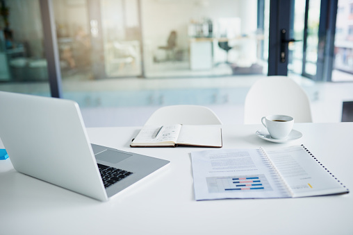 Still life shot of a laptop and paperwork on a desk in an office