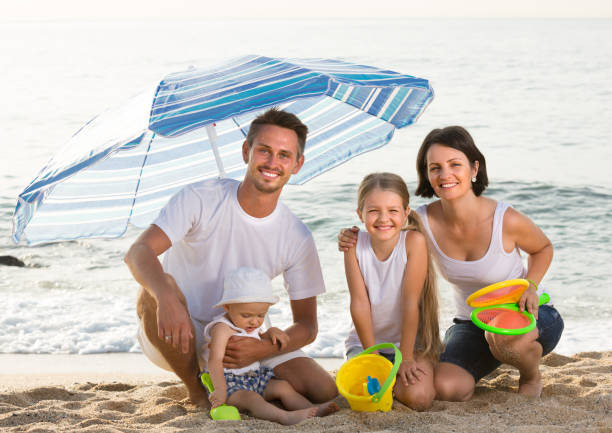 istock family sitting under umbrella on the beach 1141150008