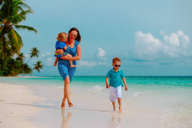 istock mother with kids play run on tropical beach 1141154003