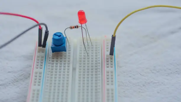 Photo of Potentiometer, resistors and red LED set up on a breadboard