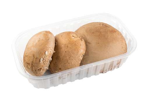 White plastic pack with whole portobello mushrooms, portabella or portobella isolated. Big brown champignons packed without label