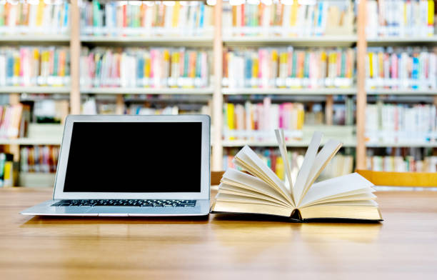 istock Laptop and open book on the table of public library 1141154902