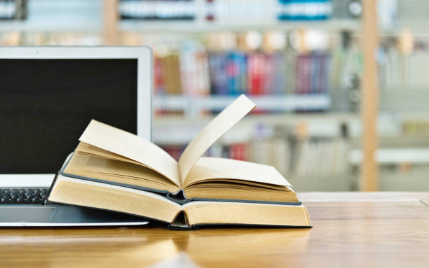 istock Laptop and open books on the table of public library 1141154903