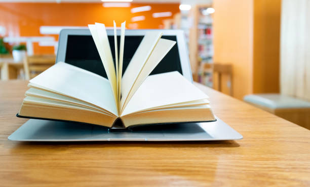 istock Laptop and open book on the table of public library 1141154928