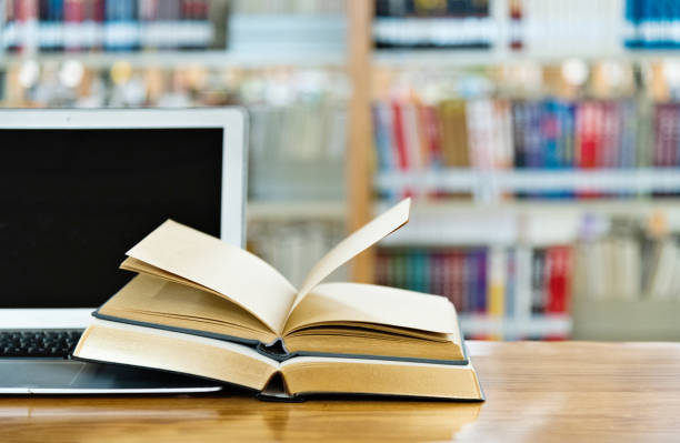 istock Laptop and open books on the table of public library 1141156076