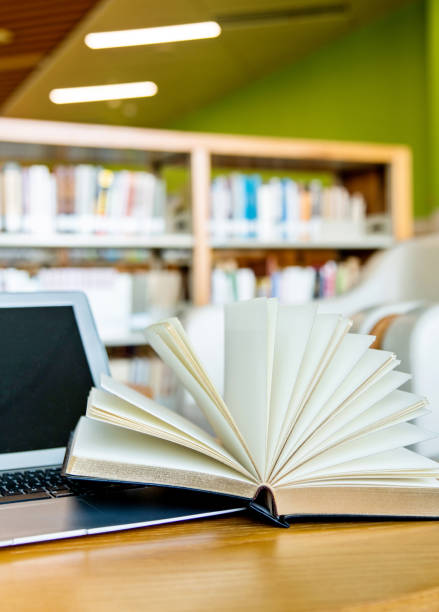 istock Laptop and open book on the table of public library 1141156208