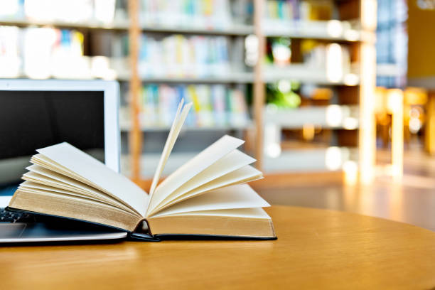 istock Laptop and open book on the table of public library 1141156365