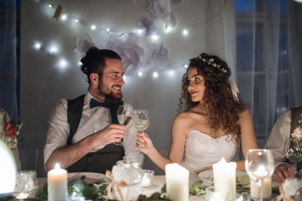 istock A young couple sitting at a table on a wedding, clinking glasses. 1141156376