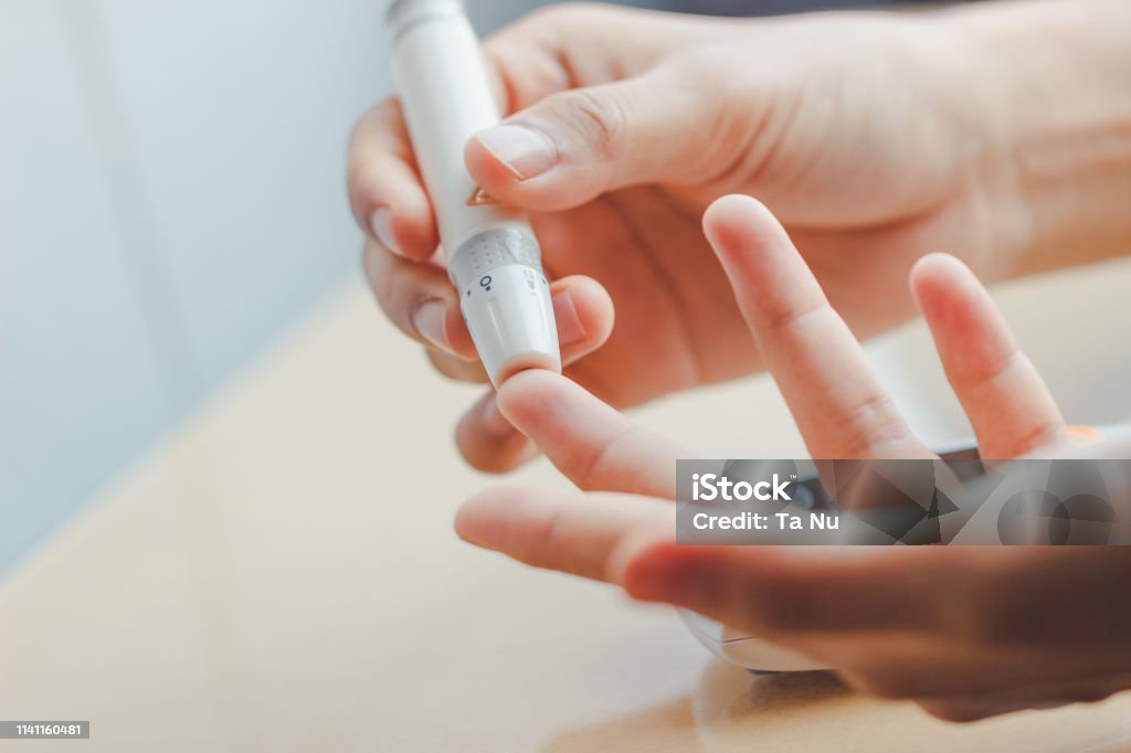 Close up of woman hands using lancet on finger to check blood sugar level by Glucose meter using as Medicine Close up of woman hands using lancet on finger to check blood sugar level by Glucose meter using as Medicine, diabetes, glycemia, health care and people concept. Diabetes Stock Photo