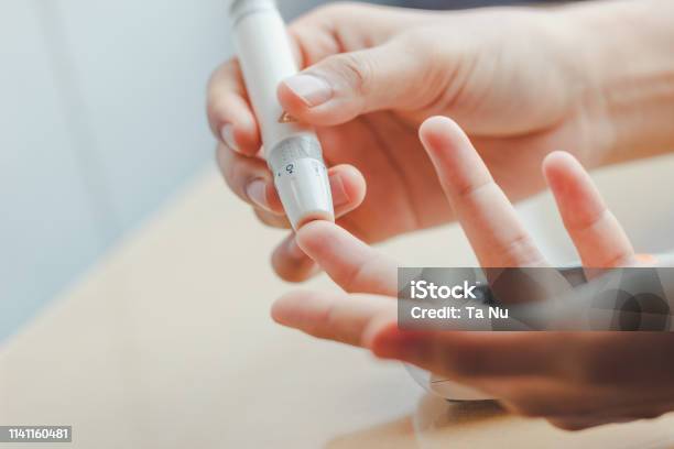 Close Up Of Woman Hands Using Lancet On Finger To Check Blood Sugar Level By Glucose Meter Using As Medicine Stock Photo - Download Image Now