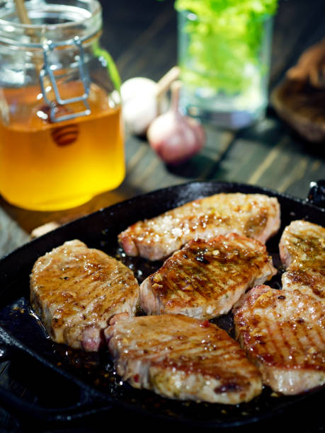 Homemade pork chops with honey and garlic glaze just brought onto the table in the frying pan