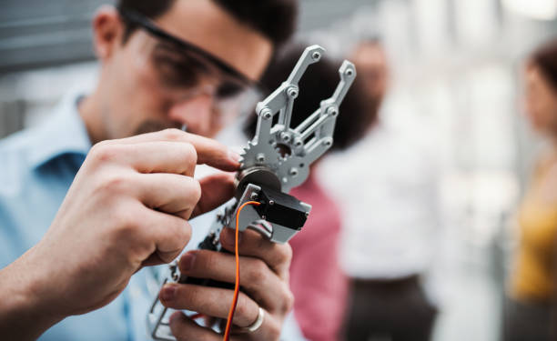 istock A young businessman or scientist with robotic hand standing in office, working. 1141164095