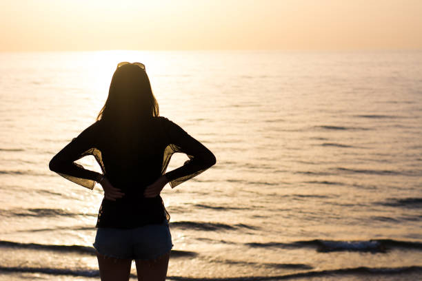 istock Woman enjoying sunset on the beach 1141167104