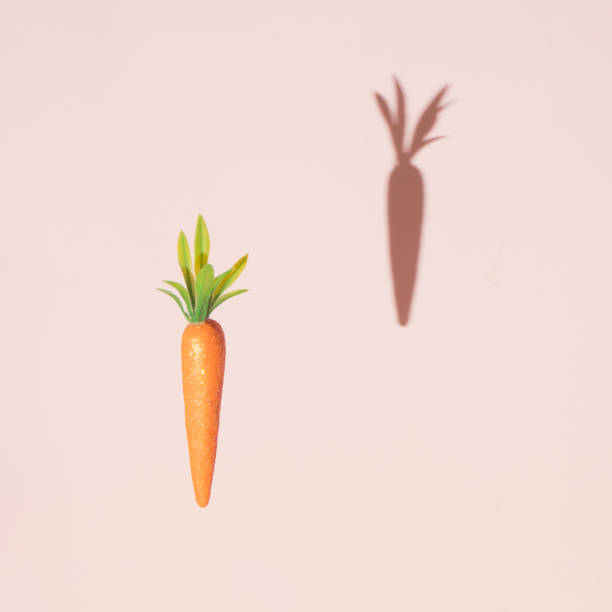 istock Carrot with creative shadow on pastel pink background. 1141171285